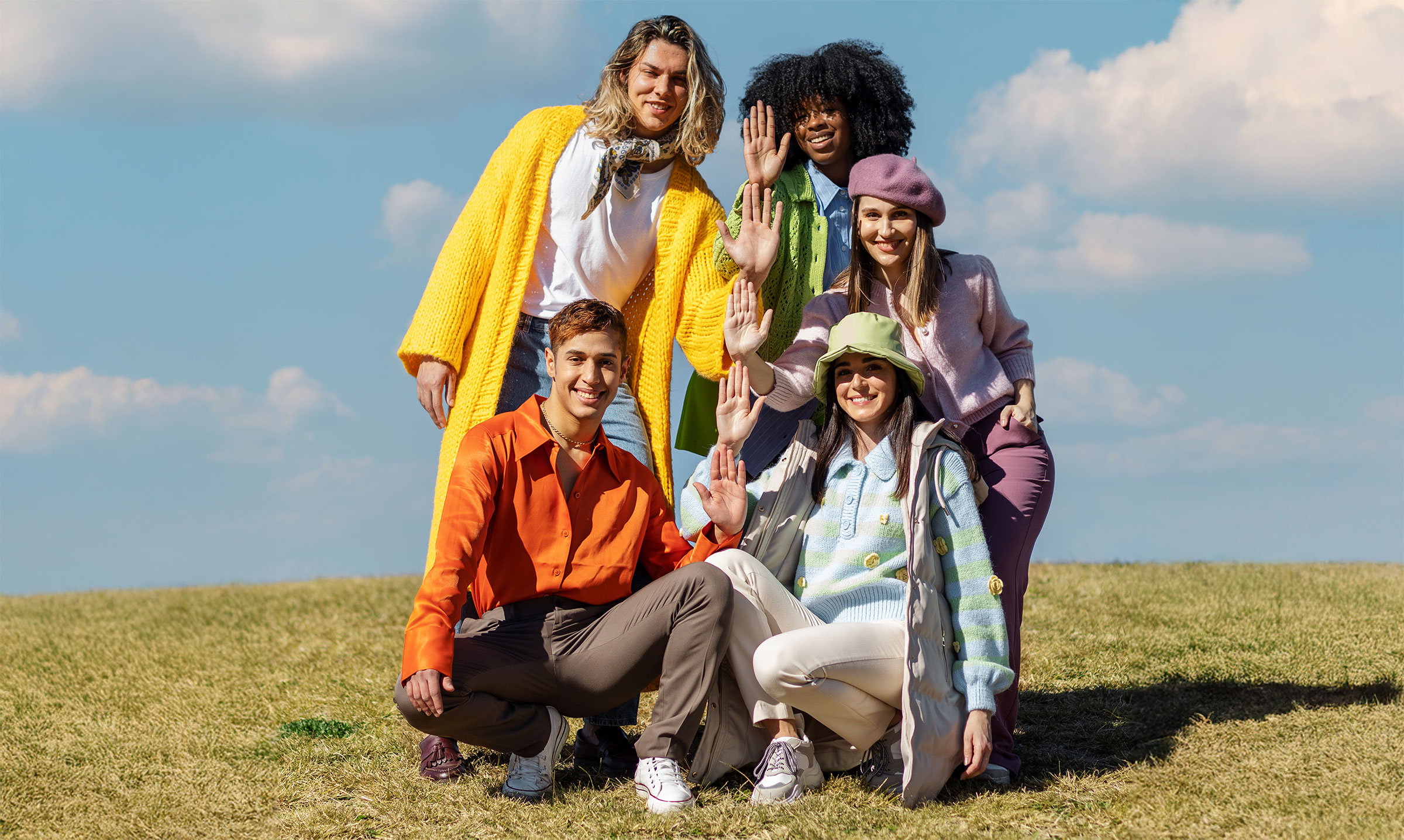 friends-posing-waving-outdoor-field